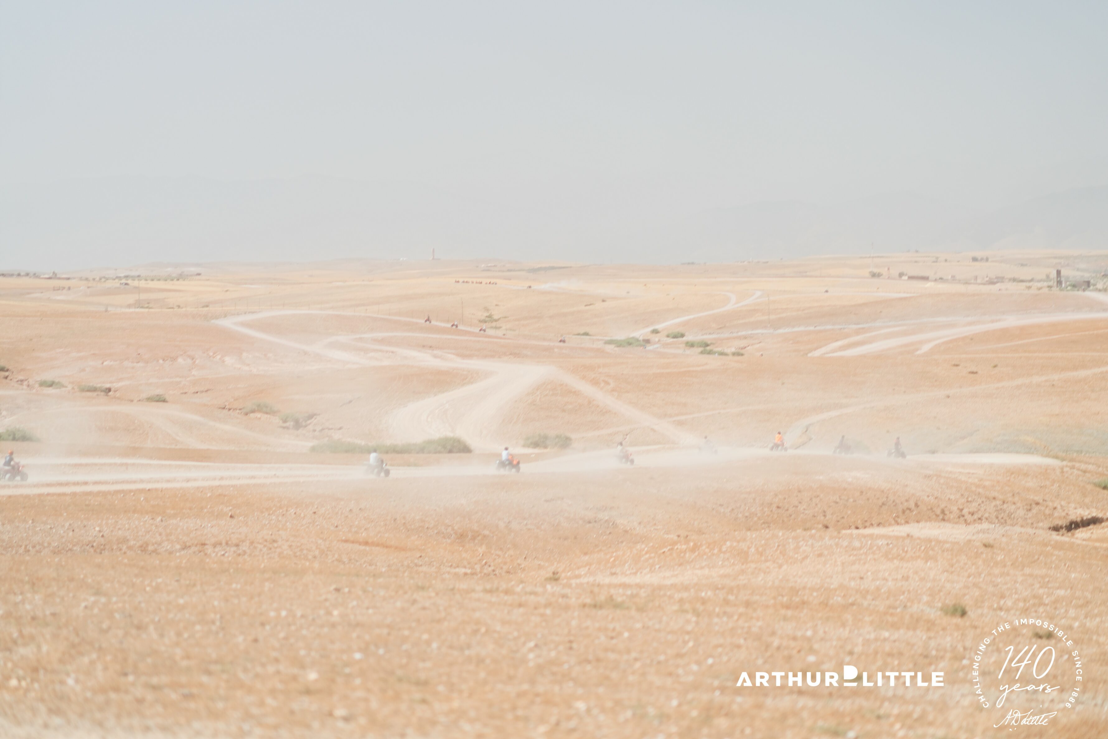 Un panorama des collines et pistes du désert d’Agafay parcourues par un groupe en quad