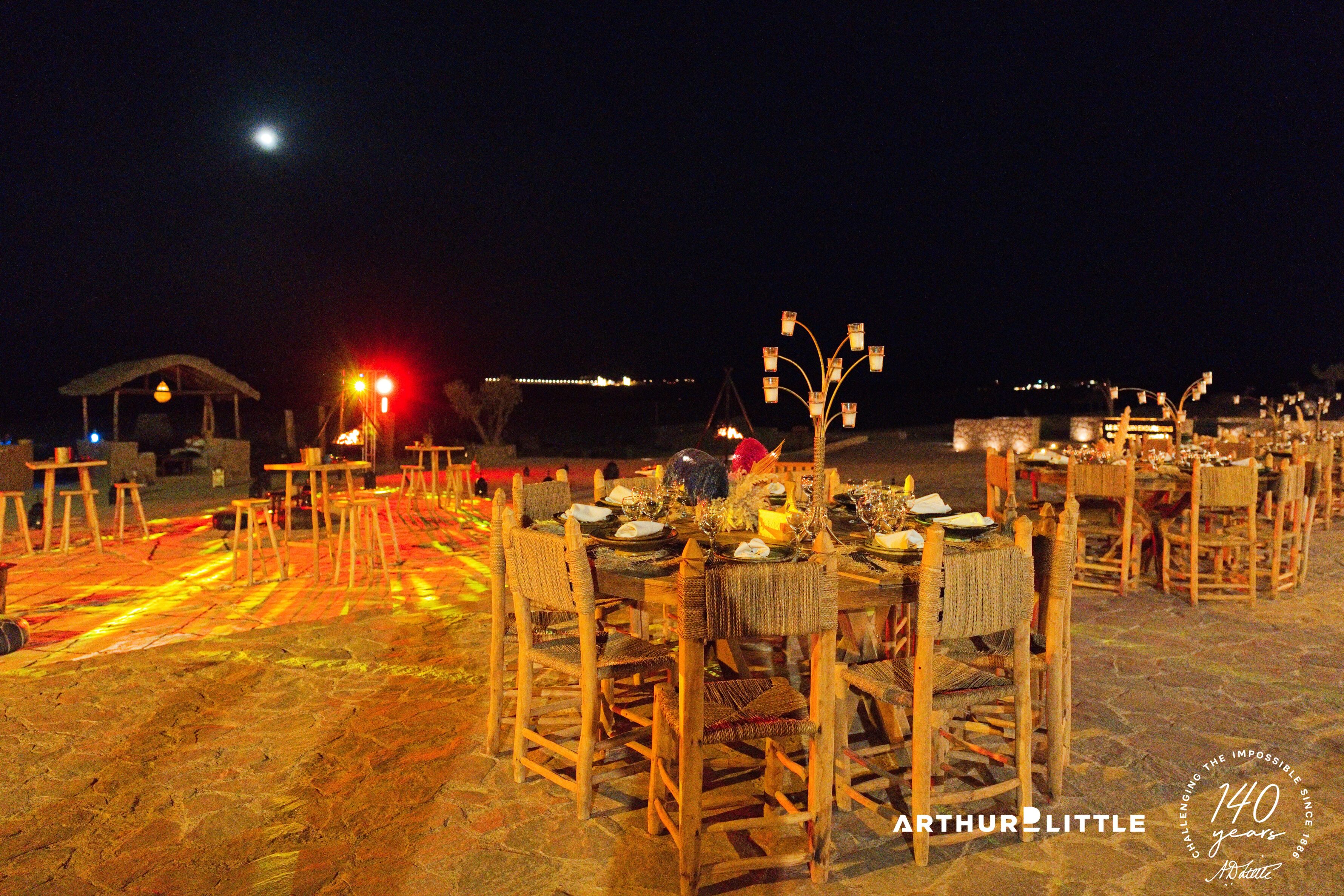Des tables dressées et éclairées pour le dîner de gala en plein air dans le désert d’Agafay
