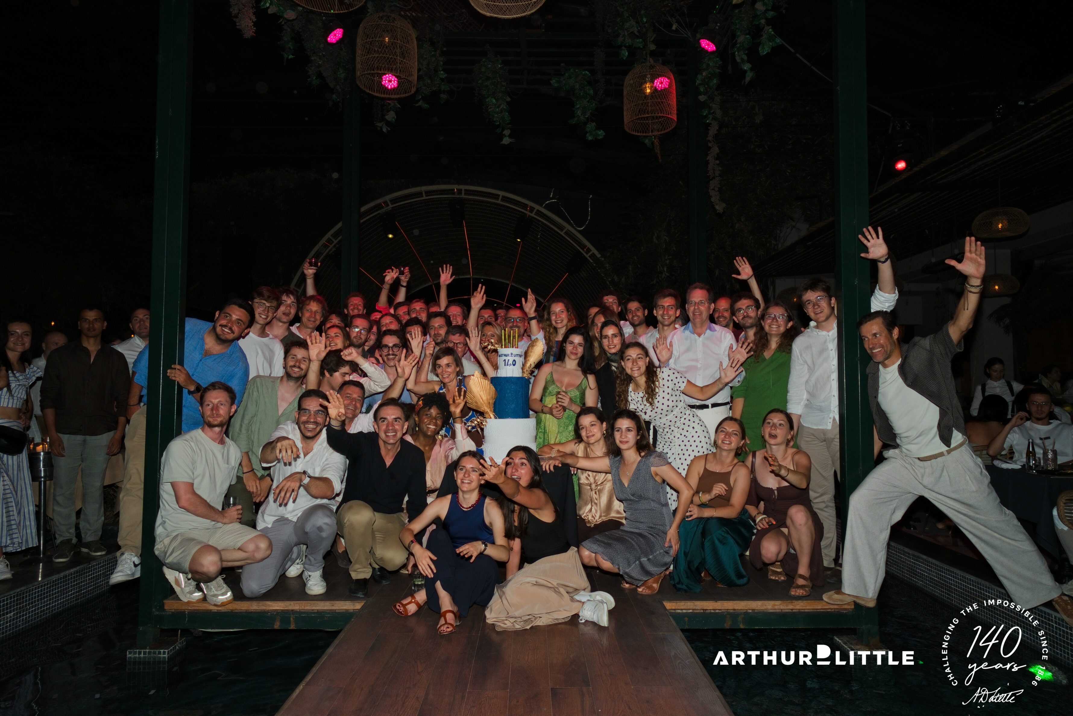 Les collaborateurs d’Arthur D. Little posent ensemble autour du gâteau des 140 ans lors de leur soirée à Marrakech