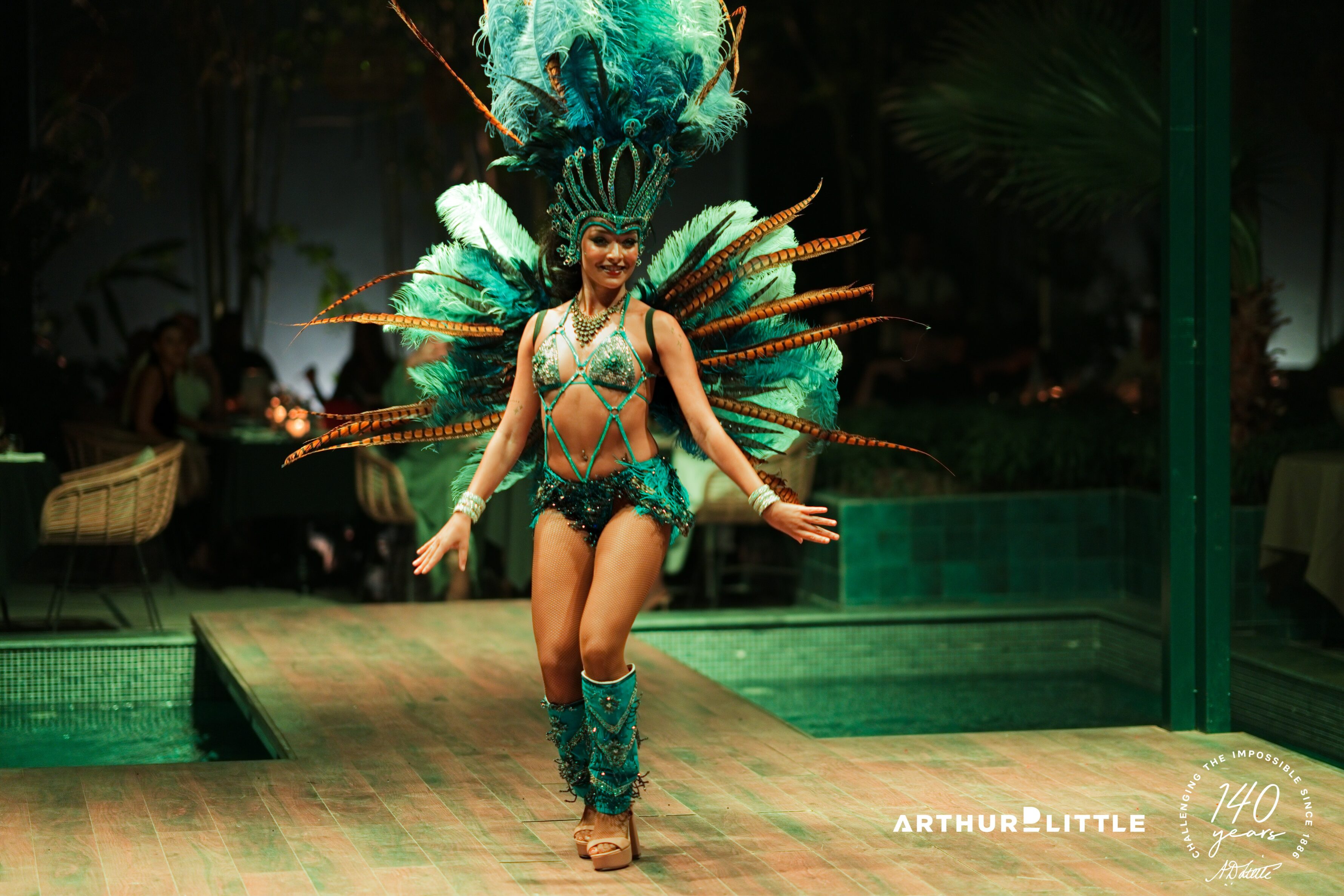 Une artiste en costume de plumes turquoise danse pendant la soirée du séminaire à Marrakech